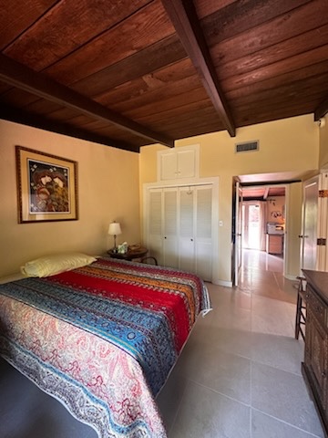 Tidy guest bedroom with wood-beam ceiling